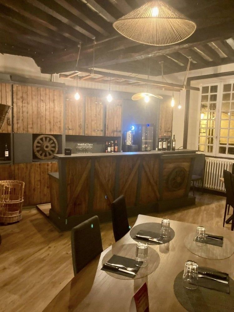 Salle de L'Abbaye avec bar en bois clair et tables dressées.